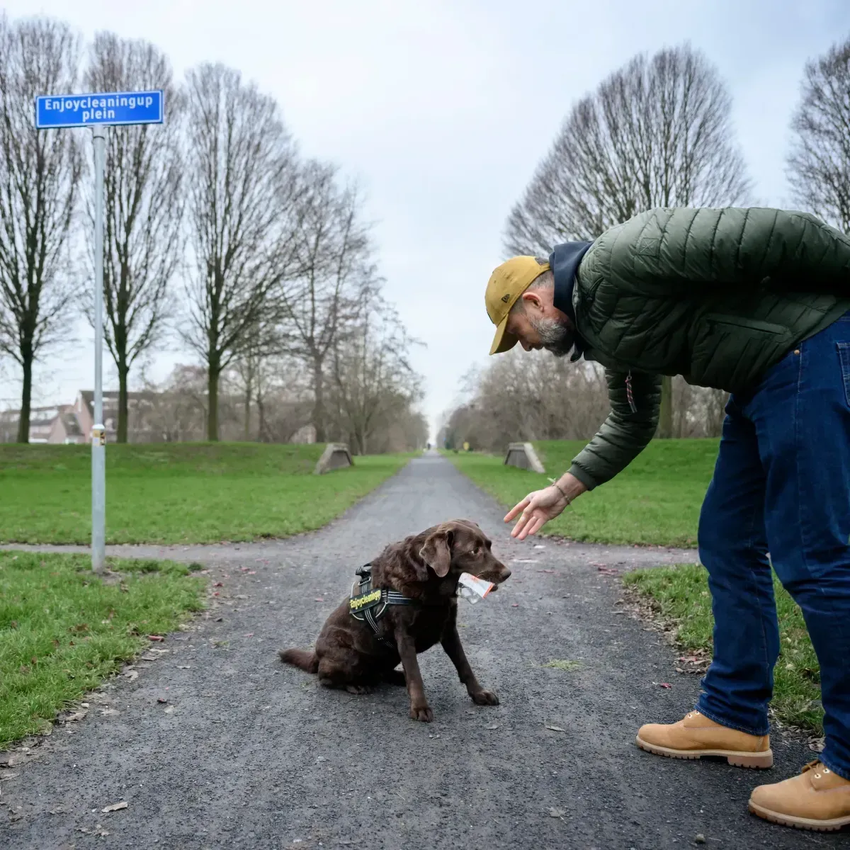 Alex en labrador Joy bij het Enjoycleaningup-plein, Joy met een stuk afval in haar bek