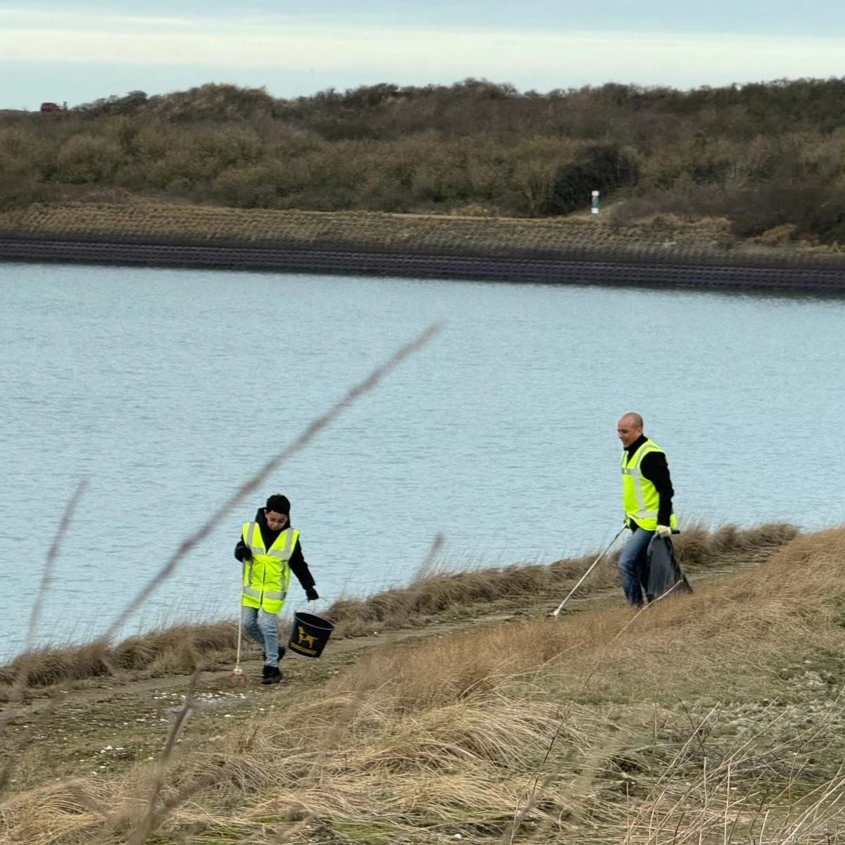 Twee vrijwilligers rapen zwerfafval op langs het water in Zeeland